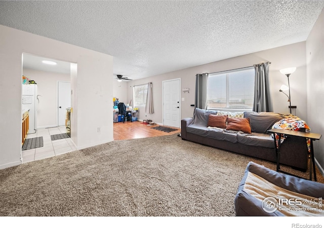 carpeted living room featuring baseboards, a ceiling fan, tile patterned flooring, and a textured ceiling