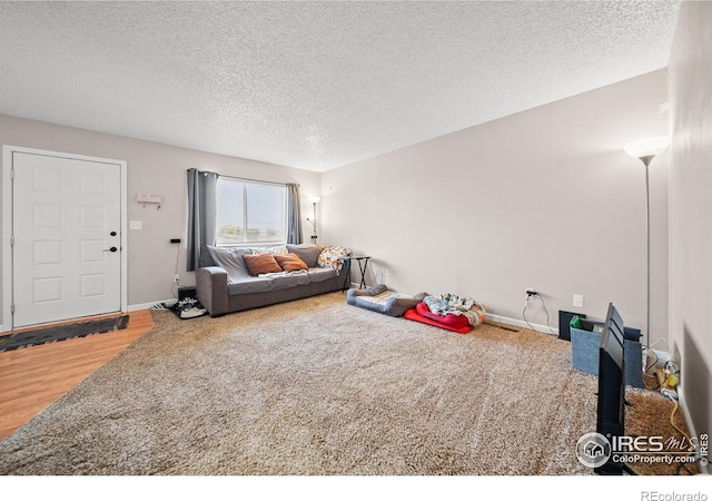 living area with baseboards, wood finished floors, and a textured ceiling