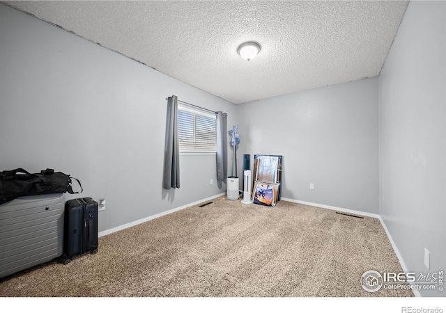 interior space featuring a textured ceiling, carpet flooring, baseboards, and visible vents