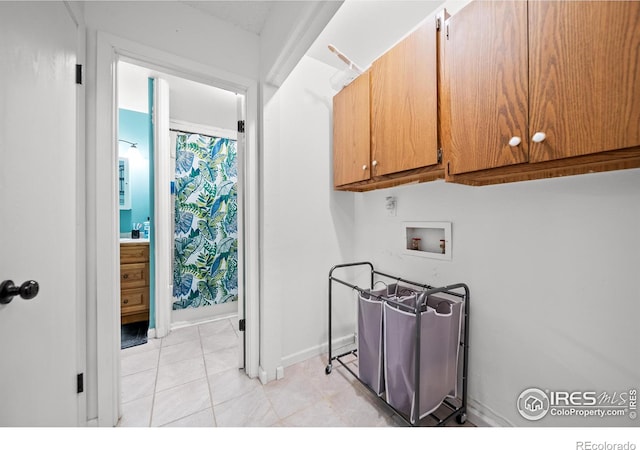 clothes washing area with cabinet space, light tile patterned floors, baseboards, and hookup for a washing machine