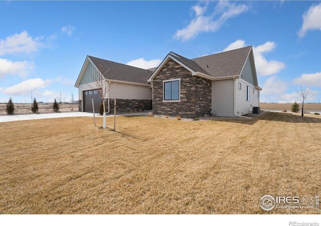 view of property exterior with concrete driveway, stone siding, central AC, a garage, and a lawn