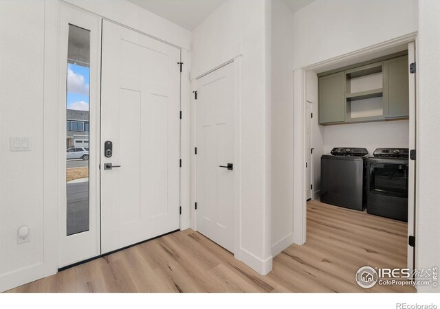 foyer entrance featuring washing machine and clothes dryer and light wood-type flooring