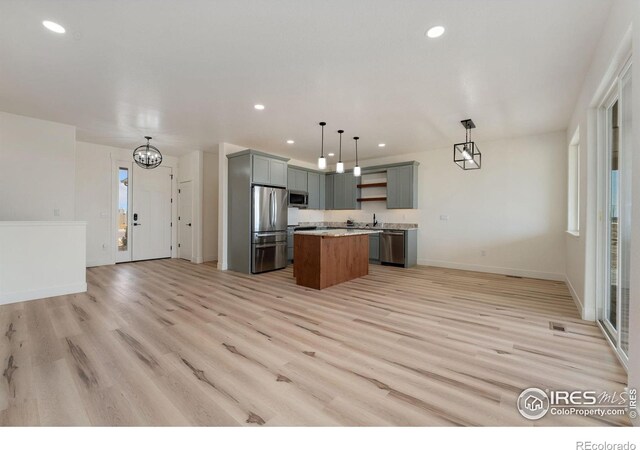 kitchen with light wood finished floors, a kitchen island, appliances with stainless steel finishes, open shelves, and open floor plan