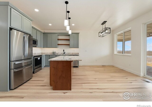 kitchen featuring light stone counters, pendant lighting, open shelves, appliances with stainless steel finishes, and light wood-style floors