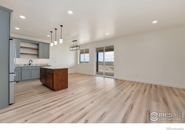 kitchen featuring open shelves, recessed lighting, light wood-type flooring, a center island, and a sink