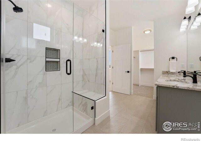 full bathroom featuring a shower stall, double vanity, baseboards, and a sink