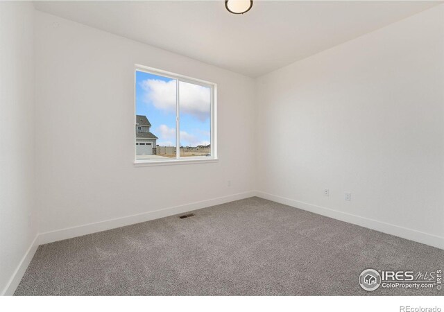 spare room featuring baseboards, visible vents, and carpet floors