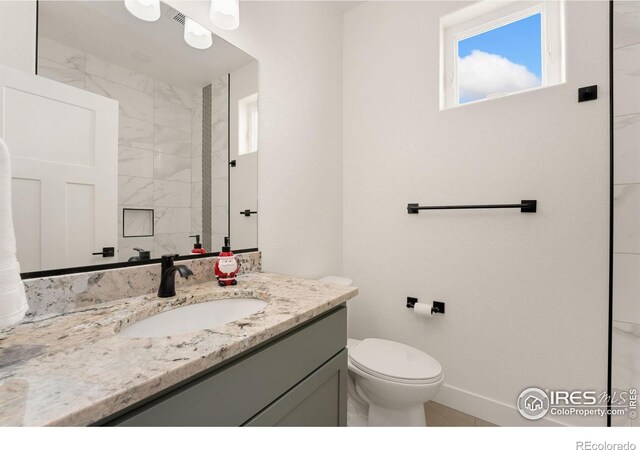 bathroom with baseboards, toilet, and vanity
