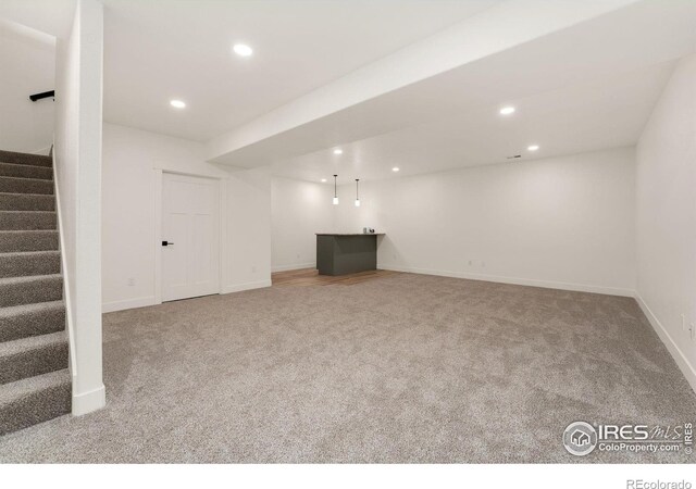 finished below grade area with carpet flooring, baseboards, indoor bar, recessed lighting, and stairway