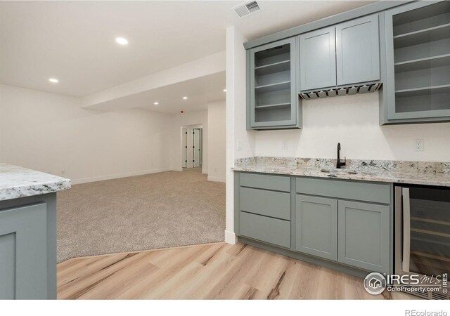 kitchen featuring visible vents, wine cooler, a sink, open floor plan, and gray cabinetry
