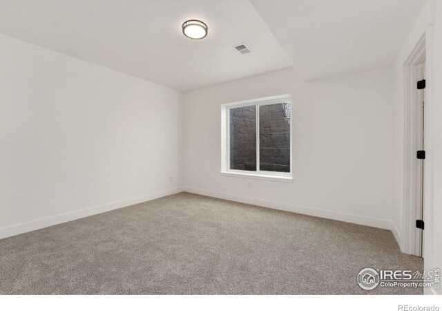 spare room featuring baseboards, visible vents, and carpet