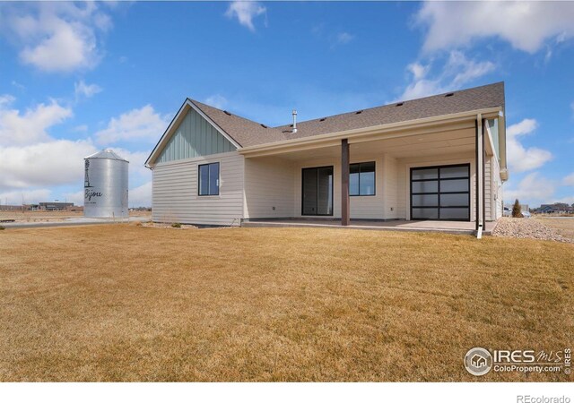back of house with a patio, a garage, board and batten siding, and a yard