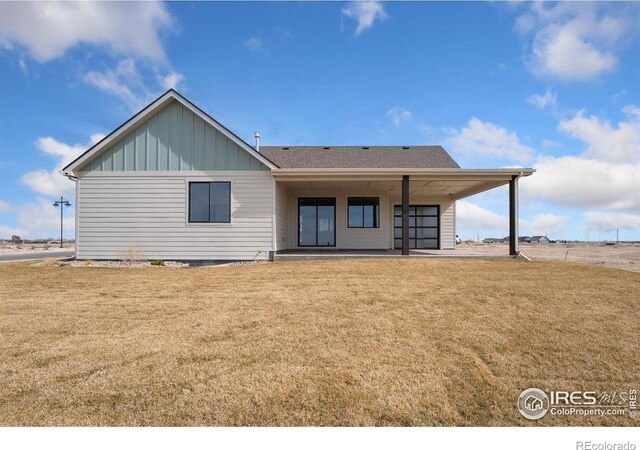 rear view of house with a patio, board and batten siding, and a yard