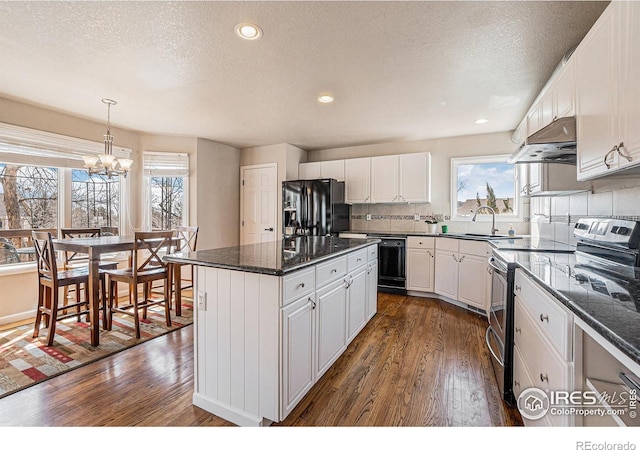 2409 Denby Ct, Fort Collins, CO 80526 - kitchen with black appliances, under cabinet range hood, dark wood-style floors, a textured ceiling, and white cabinetry