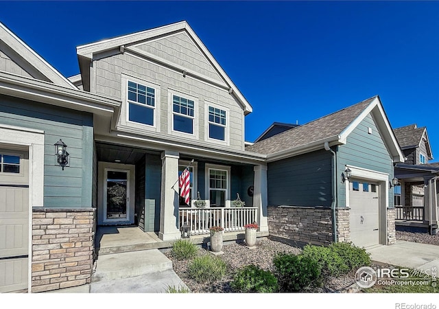 craftsman inspired home with covered porch, a garage, stone siding, roof with shingles, and driveway