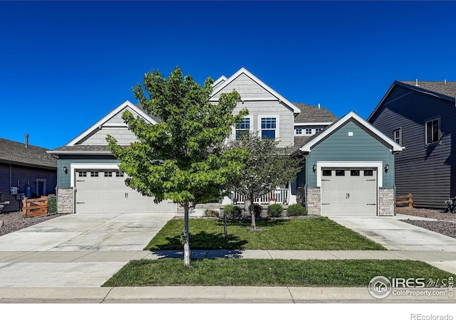 craftsman inspired home with stone siding, concrete driveway, an attached garage, and a front lawn