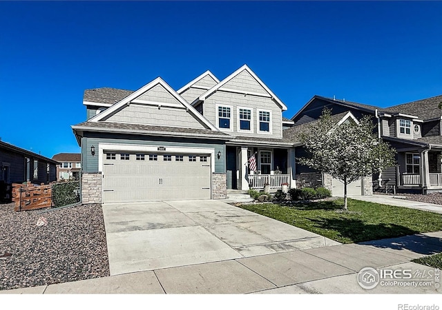 craftsman-style home featuring driveway, covered porch, stone siding, and an attached garage