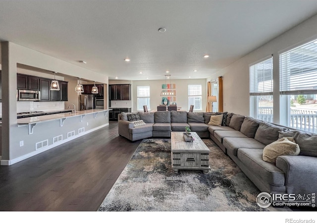 living room with dark wood-style flooring, recessed lighting, and baseboards