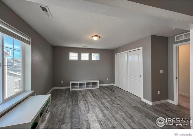 unfurnished bedroom featuring wood finished floors, baseboards, and a closet