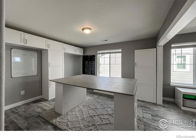 kitchen with baseboards, white cabinets, wood finished floors, and a textured ceiling