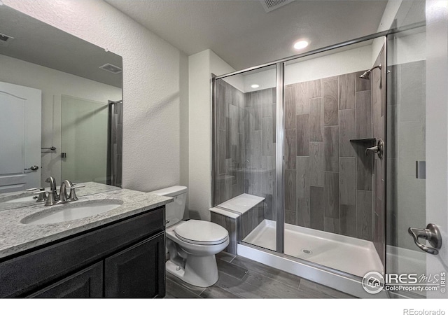 bathroom with a shower stall, vanity, and toilet