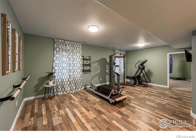 workout room featuring wood finished floors, baseboards, and a textured ceiling