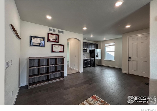 entrance foyer featuring arched walkways, dark wood-style floors, baseboards, and recessed lighting