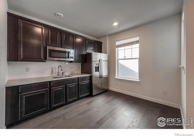 kitchen featuring stainless steel appliances, baseboards, a sink, wood finished floors, and tasteful backsplash