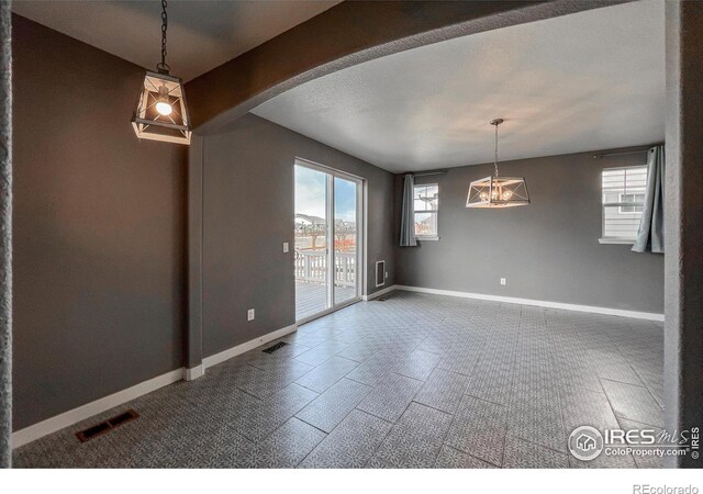 unfurnished dining area with plenty of natural light, baseboards, arched walkways, and a chandelier