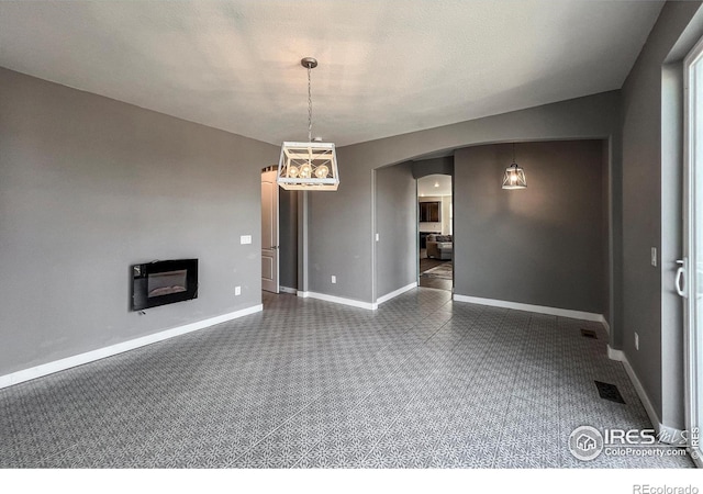unfurnished living room with arched walkways, baseboards, and a glass covered fireplace