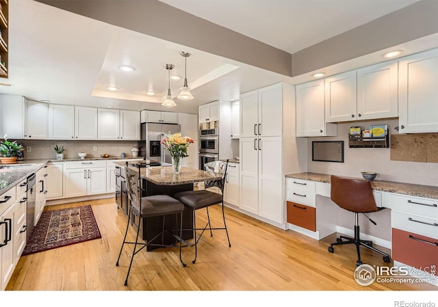 4057 Niblick Dr, Longmont, CO 80503 - kitchen featuring stainless steel appliances, a tray ceiling, light wood-type flooring, light stone countertops, and recessed lighting