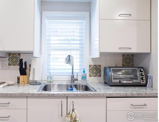 4057 Niblick Dr, Longmont, CO 80503 - kitchen featuring a sink, white cabinetry, backsplash, and light countertops