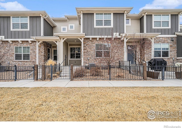 5104 River Roads Dr, Timnath, CO 80547 - view of property with a front yard, a fenced front yard, stone siding, and board and batten siding
