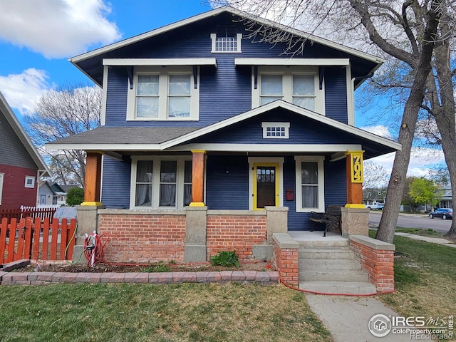 704 S 3rd Ave, Sterling, CO 80751 - view of front facade with fence, covered porch, and brick siding
