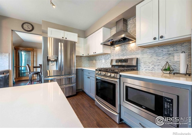 2821 5th St SW, Loveland, CO 80537 - kitchen with wall chimney exhaust hood, stainless steel appliances, light countertops, and dark wood finished floors