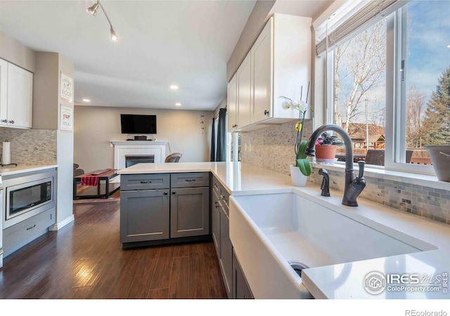 2821 5th St SW, Loveland, CO 80537 - kitchen with a sink, stainless steel microwave, backsplash, gray cabinetry, and dark wood-type flooring