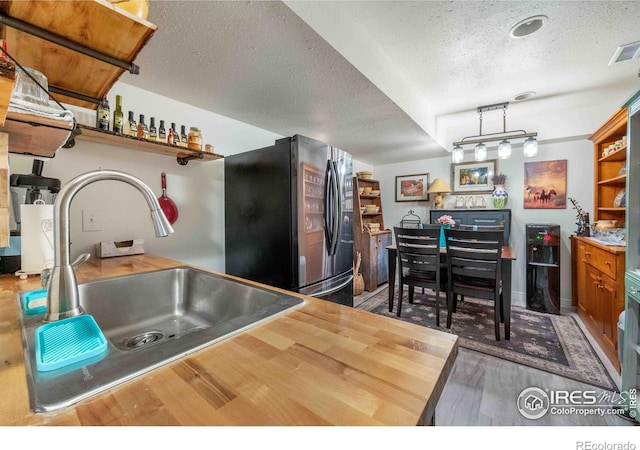 2821 5th St SW, Loveland, CO 80537 - kitchen with open shelves, wood finished floors, a sink, freestanding refrigerator, and a textured ceiling