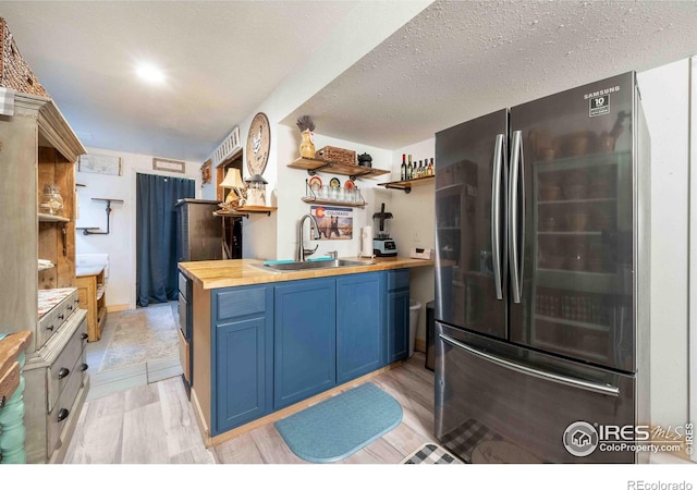 2821 5th St SW, Loveland, CO 80537 - kitchen with a sink, freestanding refrigerator, blue cabinetry, open shelves, and wooden counters