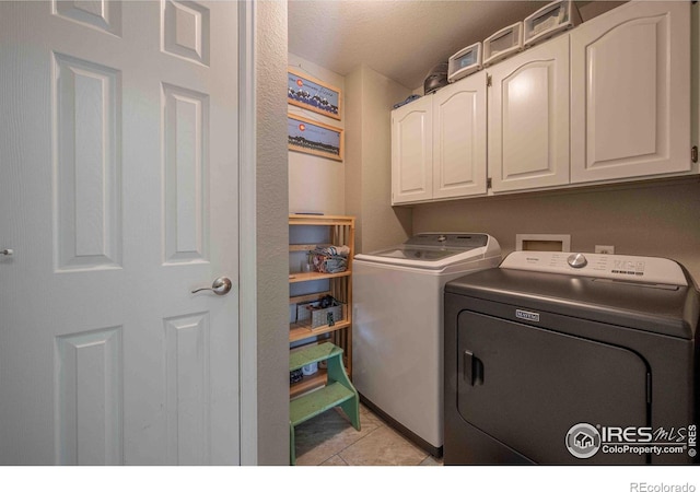 2821 5th St SW, Loveland, CO 80537 - washroom with cabinet space, a textured ceiling, washing machine and clothes dryer, and light tile patterned floors