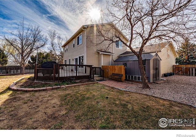 2821 5th St SW, Loveland, CO 80537 - rear view of property featuring a lawn, a fenced backyard, an outbuilding, a wooden deck, and a storage unit