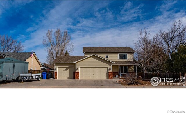 2821 5th St SW, Loveland, CO 80537 - traditional home featuring an attached garage, driveway, brick siding, and fence