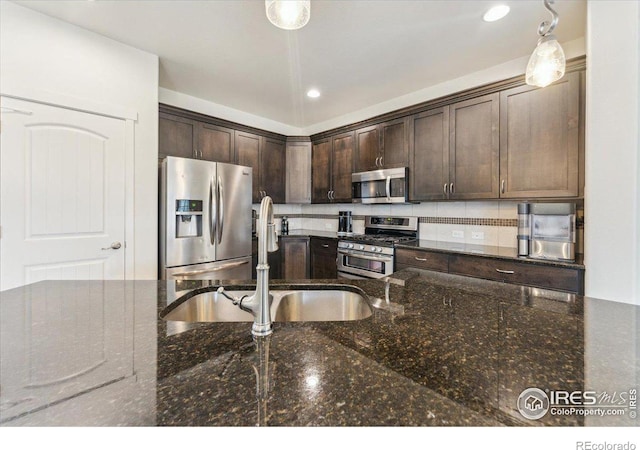403 S Maple Ave, Eaton, CO 80615 - kitchen featuring stainless steel appliances, a sink, dark brown cabinetry, dark stone countertops, and decorative backsplash