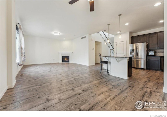 403 S Maple Ave, Eaton, CO 80615 - kitchen featuring stainless steel fridge with ice dispenser, dark countertops, wood finished floors, a kitchen bar, and recessed lighting