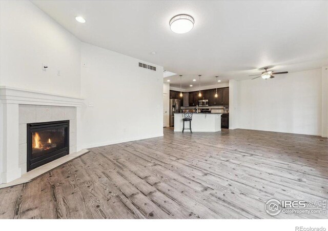 403 S Maple Ave, Eaton, CO 80615 - unfurnished living room with light wood-style floors, a tile fireplace, ceiling fan, and recessed lighting