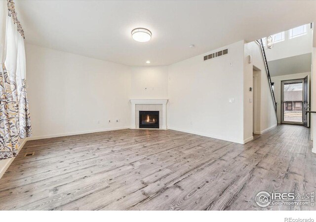 403 S Maple Ave, Eaton, CO 80615 - unfurnished living room with wood finished floors, a tiled fireplace, and baseboards