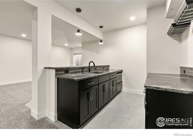 3364 Danzante Bay Ct, Berthoud, CO 80513 - kitchen with a sink, dark cabinetry, a peninsula, baseboards, and dark stone counters