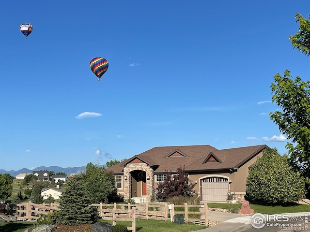 1046 Greens Pl, Erie, CO 80516 - view of front of property with fence, an attached garage, stone siding, and a mountain view