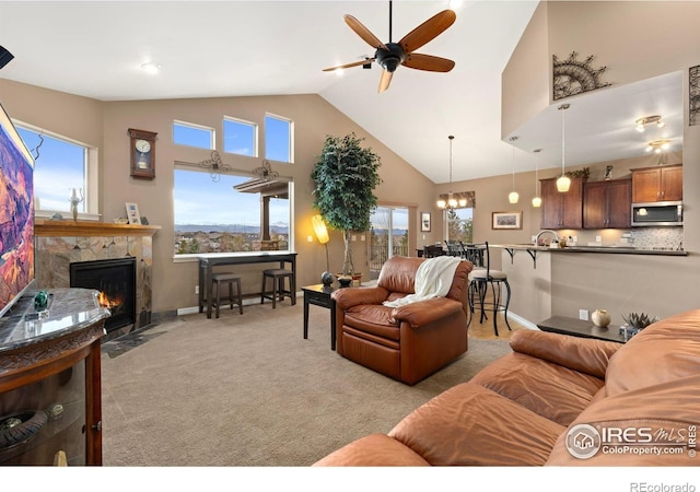 1046 Greens Pl, Erie, CO 80516 - living room featuring ceiling fan, light colored carpet, a fireplace, baseboards, and a chandelier
