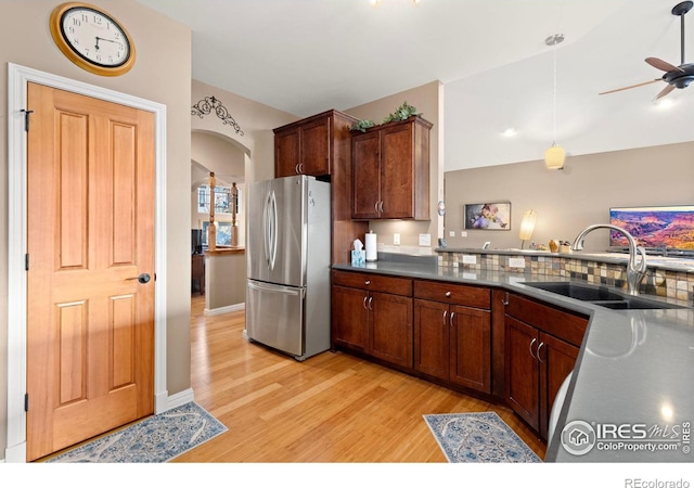 1046 Greens Pl, Erie, CO 80516 - kitchen featuring freestanding refrigerator, a sink, light wood-type flooring, arched walkways, and dark countertops