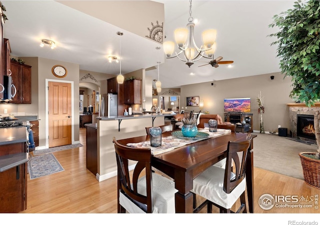 1046 Greens Pl, Erie, CO 80516 - dining room featuring light wood-style flooring, a chandelier, arched walkways, a premium fireplace, and ceiling fan